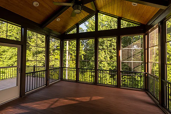 Modern screened porch with plastic windows and composite floor with summer woods in the background.